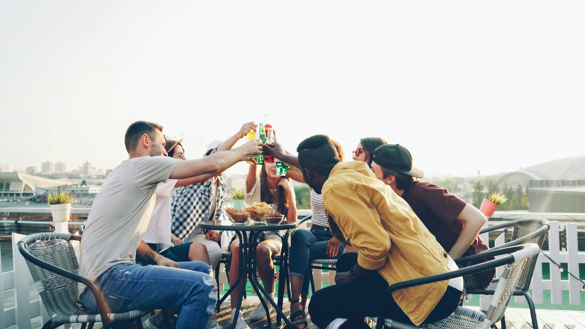 Friends toasting drinks on a sunny rooftop patio at golden hour
