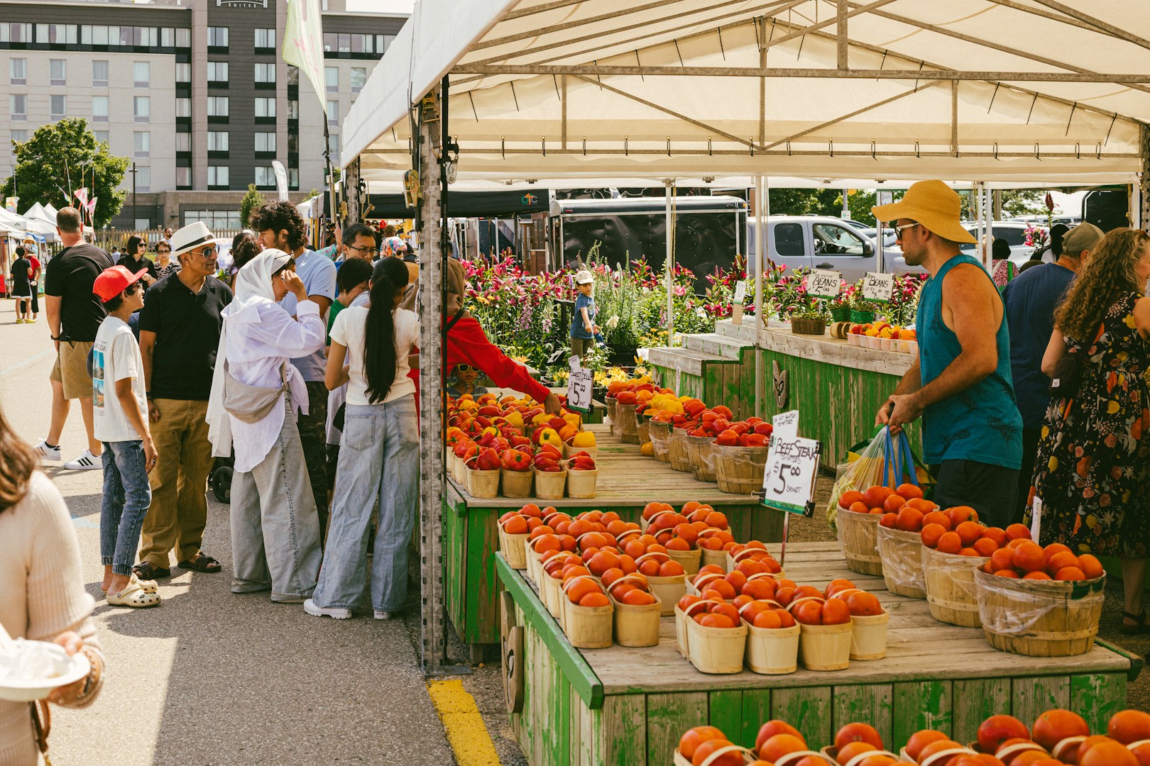 People browsing colorful produce stalls at an outdoor farmers market