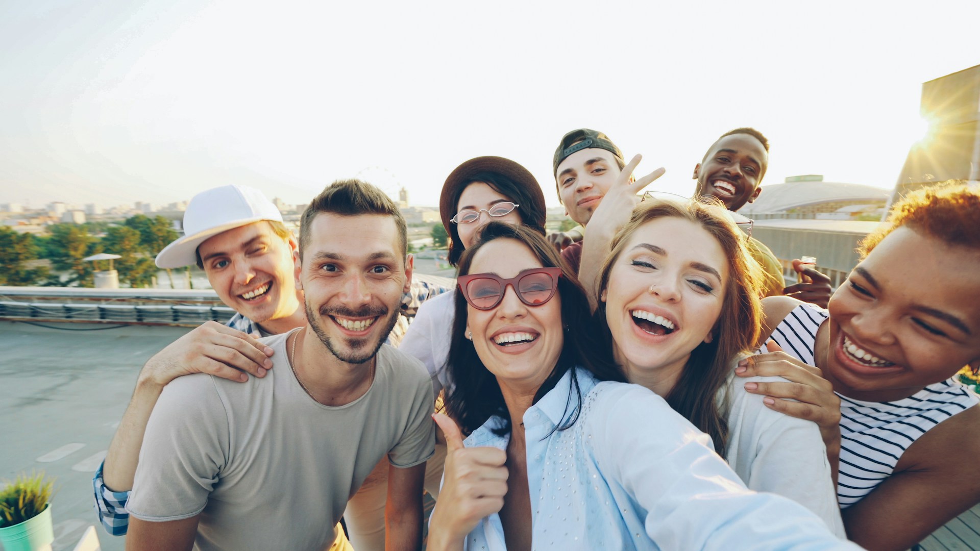 Group of friends at a rooftop gathering at sunset, laughing together