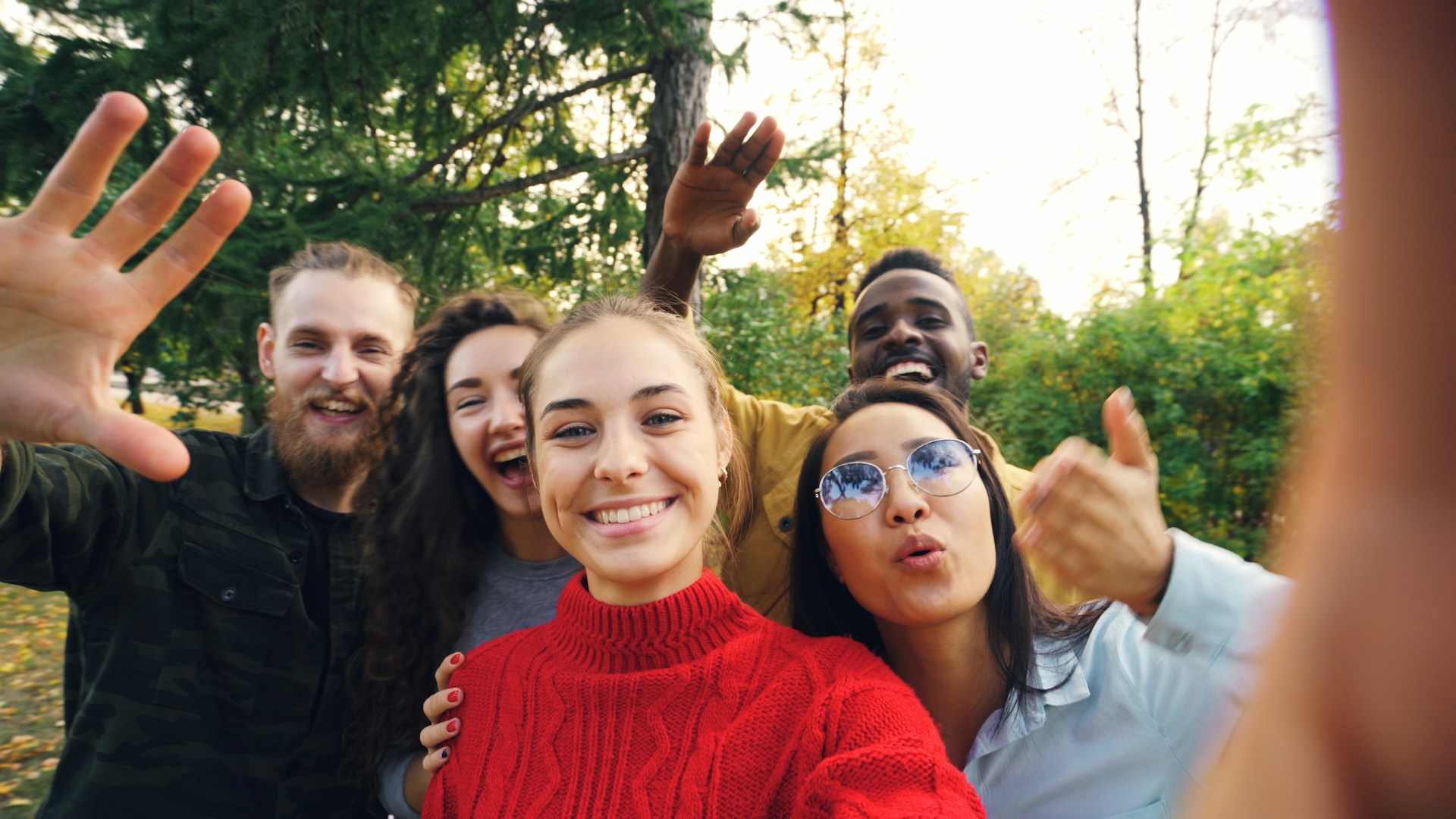 A diverse group of friends taking a selfie outdoors in autumn light
